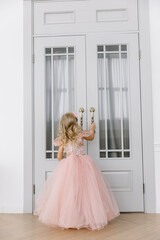 A little girl in a long and lush pink dress looks in. The concept of the new year.