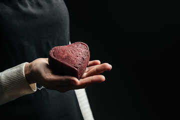 woman holding red Heart shaped hard cheese on a dark background. Valentine's day concept