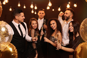 Fototapeta na wymiar Happy friends with glasses of sparkling wine celebrating New Year indoors