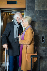 Elderly man kissing his partner in the hotel lobby