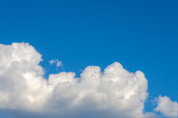 Naklejka na ściany i meble Beautiful white fluffy cloud floating in blue sky in sunny day, Cumulus are clouds which have flat bases and are often described as puffy, Horizon nature background with free copy space.