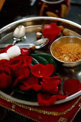 Obraz na płótnie Canvas Red rose flowers with Diwali Diya kept in the middle Used for worship Items for the Indian Yajna ritual red rose petals and copper plate with rice for Hindu Vedic Yajna Close up Wedding ceremony 