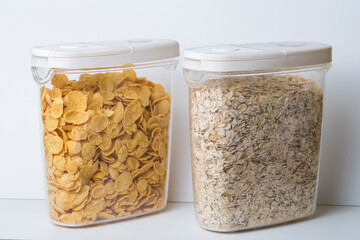 oatmeal flakes and corn flakes in plastic food container jars with white lid isolated on white background