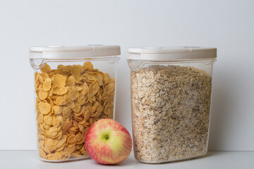 oatmeal flakes and corn flakes in plastic food container jars with white lid and a red apple...