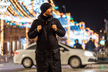 male tourist with a backpack walks through the night city in winter. got lost