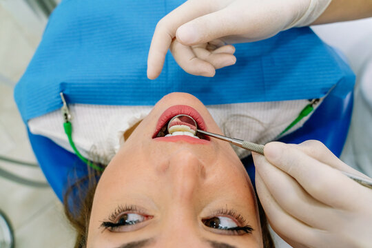 Unrecognizable dentist examining teeth of woman