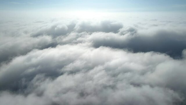 Aerial shot of flying over a layer of soft clouds at dawn