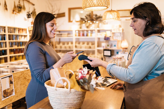 Pregnant female paying with smartphone in eco friendly store