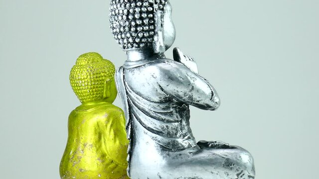 Two metal Budda statues/figures rotating on rotating plate