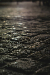 Old stone tiles, on the background of a house with illumination in defocus, photo at night