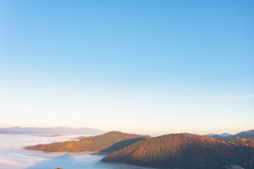 Fototapeta na wymiar Highland with colorful forests covered with fog at sunrise