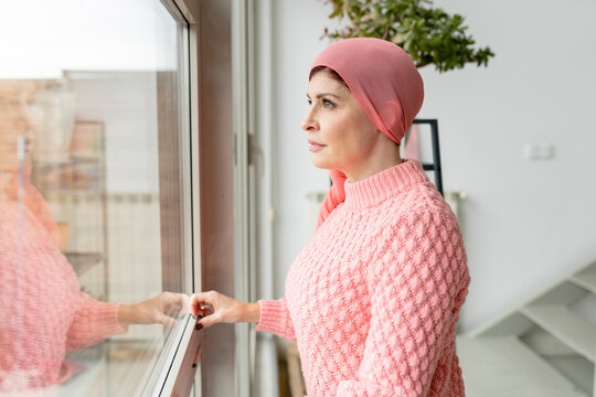 Woman in headscarf looking out window