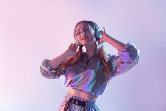 Futuristic female in stylish outfit standing in studio with neon illumination