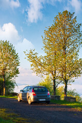 Fototapeta na wymiar car on the hill. beautiful countryside scenery in spring. travel early in the morning. trees on the slope beneath a blue sky with clouds.