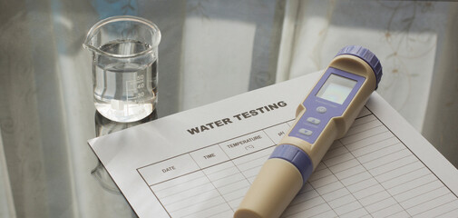 Portable pH meter  and water testing sheet on the table. Becker with water,  ORP and temperature meter on the desk. © hunterpic2013