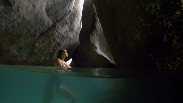 Partly underwater shot of a woman in a cave on Virgin Gorda, slow motion