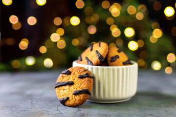 orange cookies with black stripes in bowl and fir tree branches. Christmas dessert. Concept for...