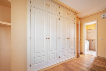 Bedroom with white walk-in closet and en-suite bathroom with parquet flooring
