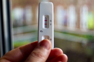 hand holding up a positive lateral flow test for Covid 19