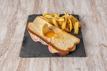 Cuban sandwich with fried egg, cheese and boiled ham garnished with homemade chips on wooden table