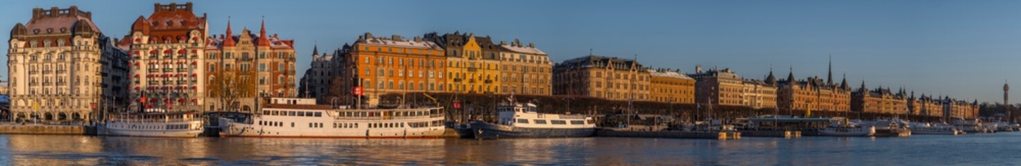 Fototapeta na wymiar Panorama view at the bay Nybroviken and street Strandvägen with commuting boats and apartments, hotels and office buildings a snowy winter day afternoon in Stockholm