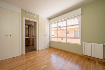 Fototapeta premium Empty room with greens, en-suite bathroom and oak floors with large windows.