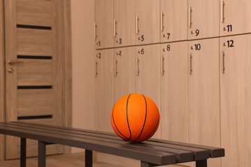 Orange basketball ball on wooden bench in locker room