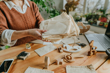 Young woman holding linen bags for packing purchase at her workshop