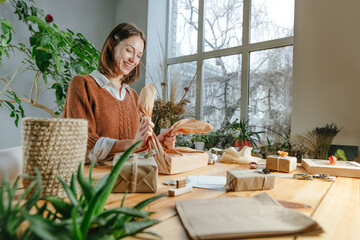 Young woman packing gift box in fabric furoshiki