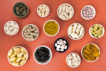 doses of pills top view. dietary supplement capsules, pills and softgels on coral background. immune prevention care concept
