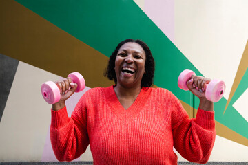 Cheerful woman exercising with pink dumbbells