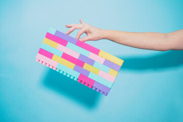 Arm of woman holding colorful pastel colored toy blocks against blue background