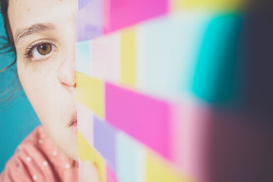 Face of adult woman peeking at camera from behind toy blocks