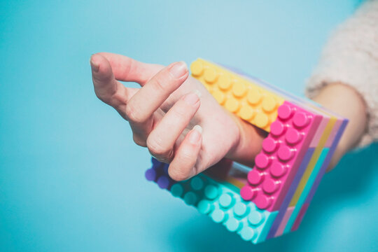 Arm of woman wearing colorful cube made of pastel colored toy blocks as bracelet