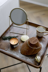Gold chain on a wooden stand Accessories for a woman on a stylish table in the living room Mirror mug and candle for a cozy and festive atmosphere in the house