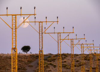 luna entre torres alumbrado inicio pista de aterrizaje en aeropuerto >Lleida-Alguaire