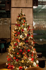 Christmas tree decorated with red and yellow balls and a garland of candles on the background of...