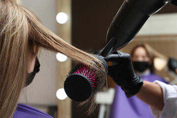 Professional stylist working with client in beauty salon, closeup. Hairdressing services during Coronavirus quarantine