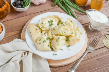 Dumplings with filling on a white plate on a wooden background