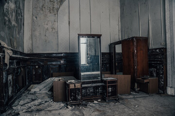 An antique room with furniture in an abandoned house. Old mirror. Reflection of light in a mirror. Shabby walls with mold. Wooden furniture. A room in an abandoned manor.