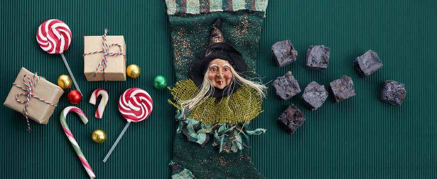 Befana sock with sweet coal and candy on dark greeen background. Italian Epiphany day tradition.