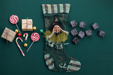 Befana sock with sweet coal and candy on dark greeen background. Italian Epiphany day tradition.