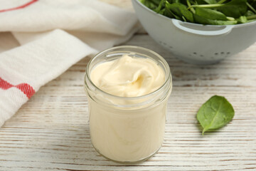 Fototapeta na wymiar Jar of delicious mayonnaise and fresh spinach on white wooden table