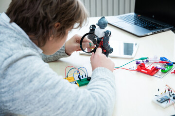 Teenager boy with instructor at robotics school makes robot managed from the constructor, child...