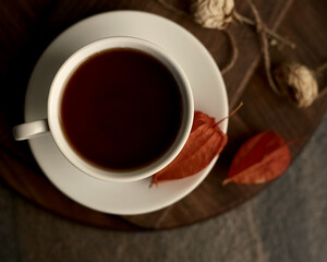 Cup of tea on a wooden board. There are dried flowers near the cup. Flat lay. Shallow depth of field