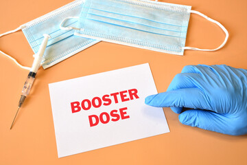 hand of doctor indicates white paper with text Covid-19 Booster Dose. Concept of Combating the...
