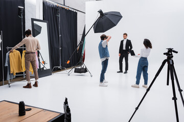 multiethnic team working during photo session with trendy model in studio.