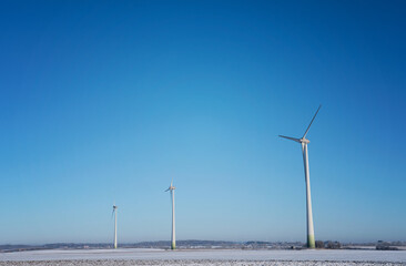 Three wind power stations on a cold day with snow on the agricultural field. Photo taken in Skåne,...