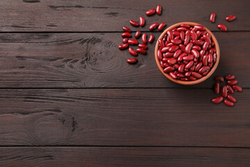 Raw red kidney beans with bowl on wooden table, flat lay. Space for text