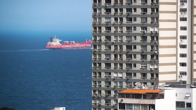 High-Rise Building And A Tanker Sailing In The Background On The Sea